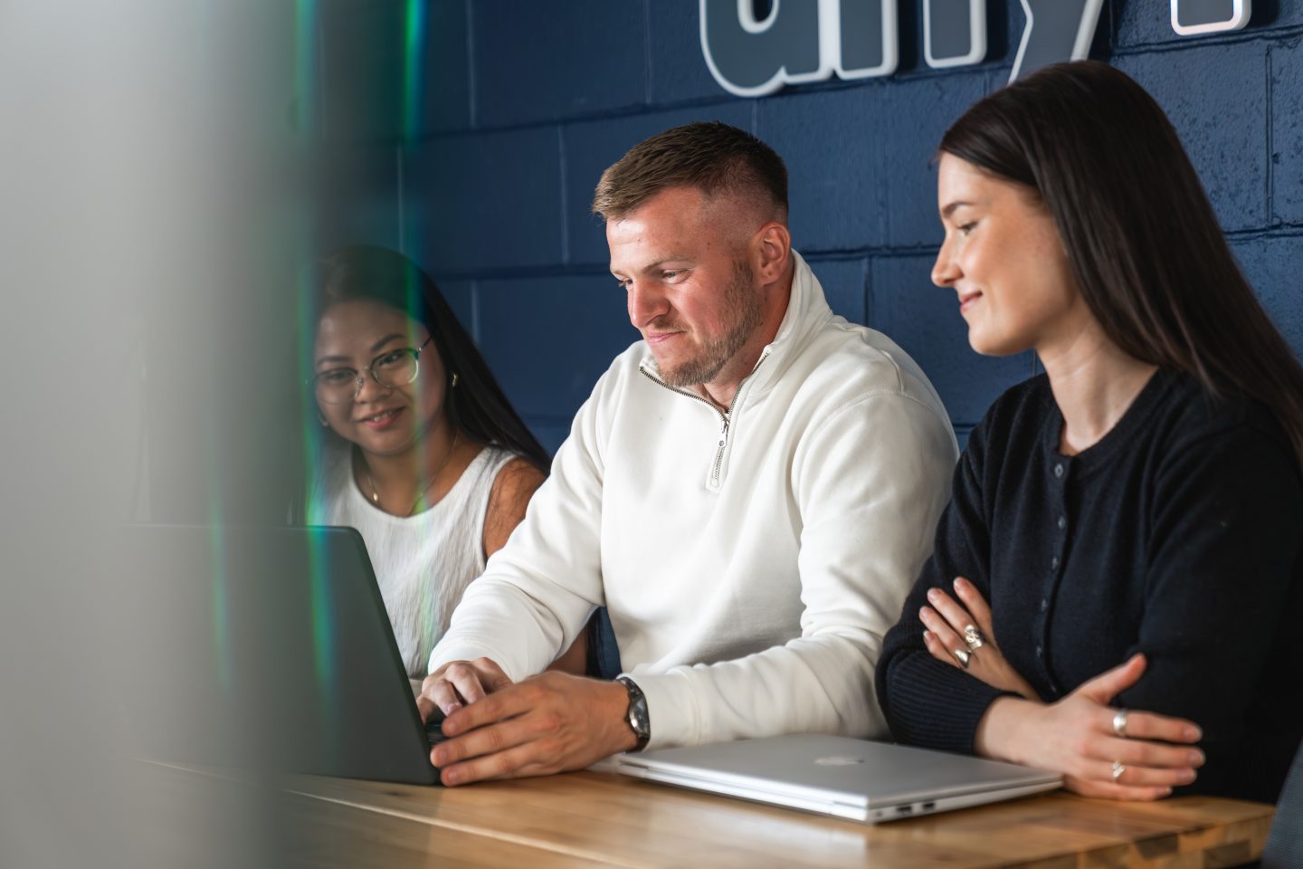 Three people looking at a laptop in a meeting room
