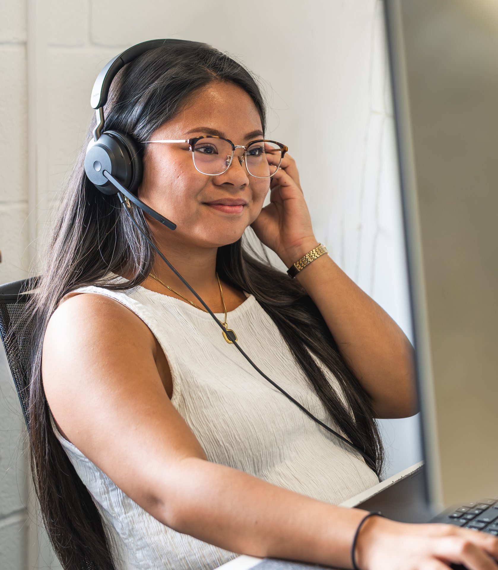 A person is working at their desk with a headset on, looking at their computer