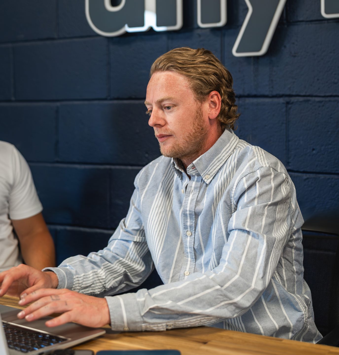 A person in a meeting typing on their laptop