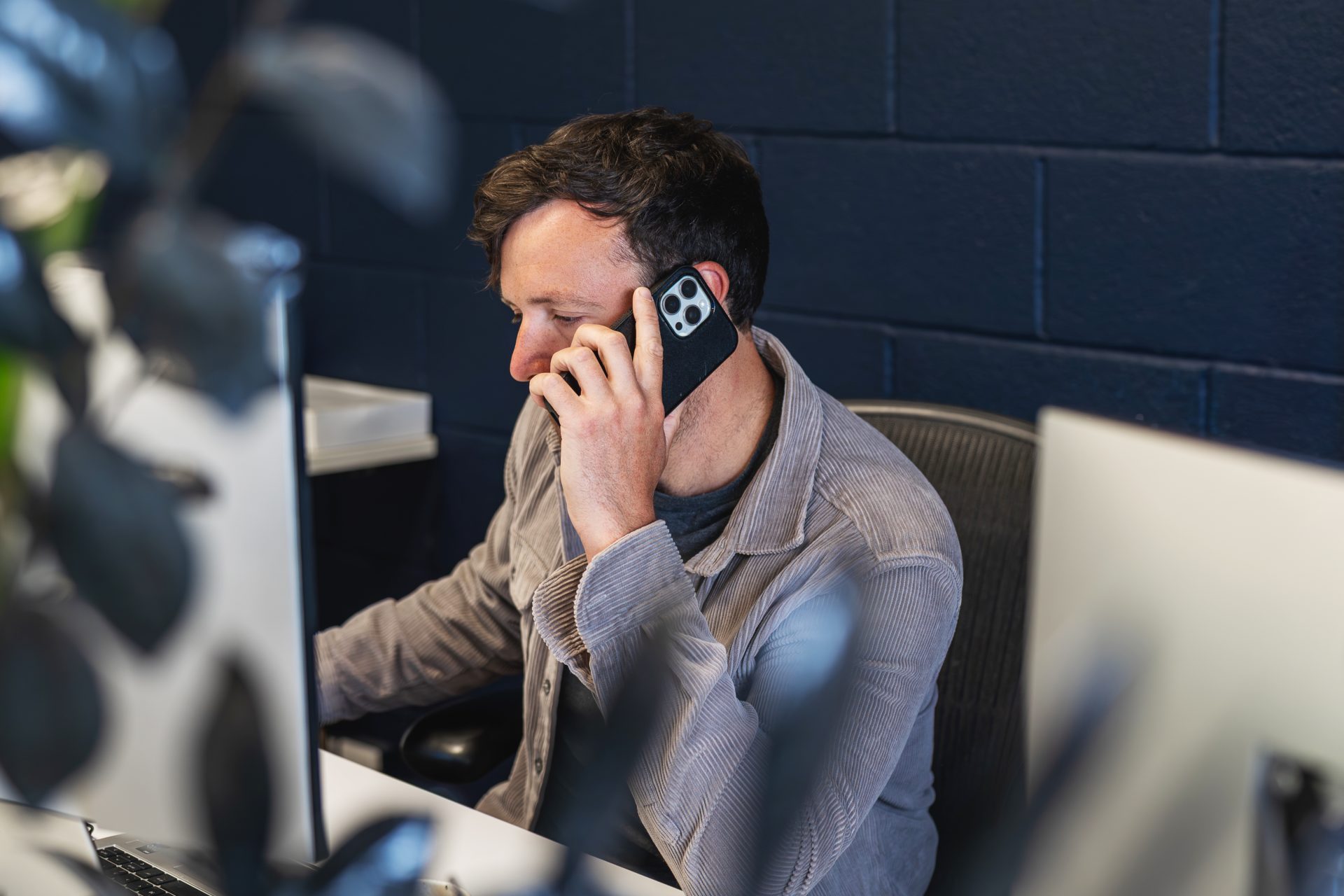 A person working on their desk and on the phone