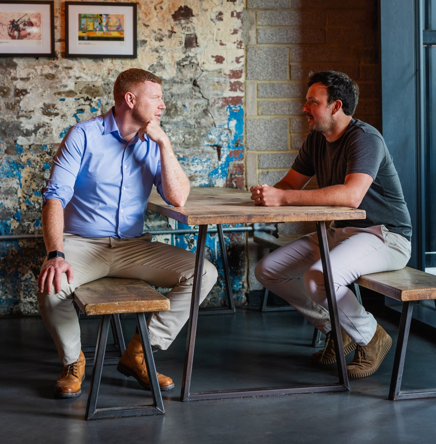 Two people are sitting across from each other at a stylish restaurant, engaged in conversation