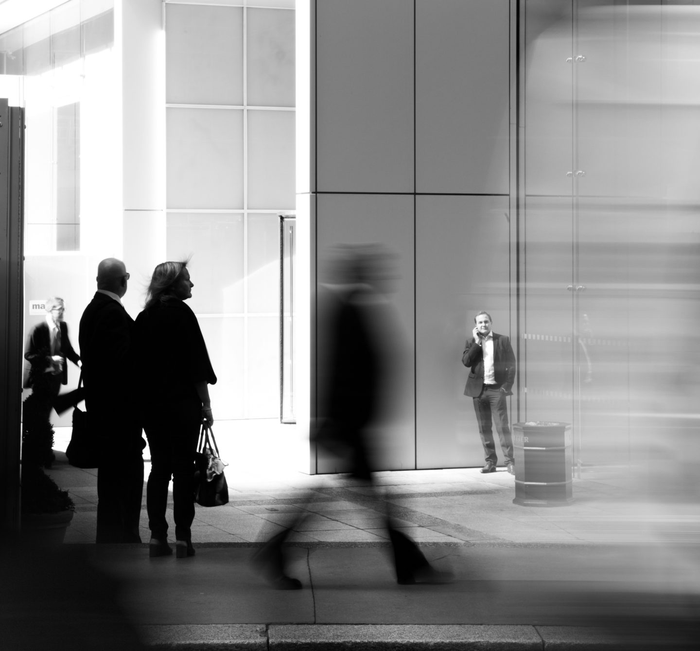 A long exposure photograph of people walking in front of corporate buildings