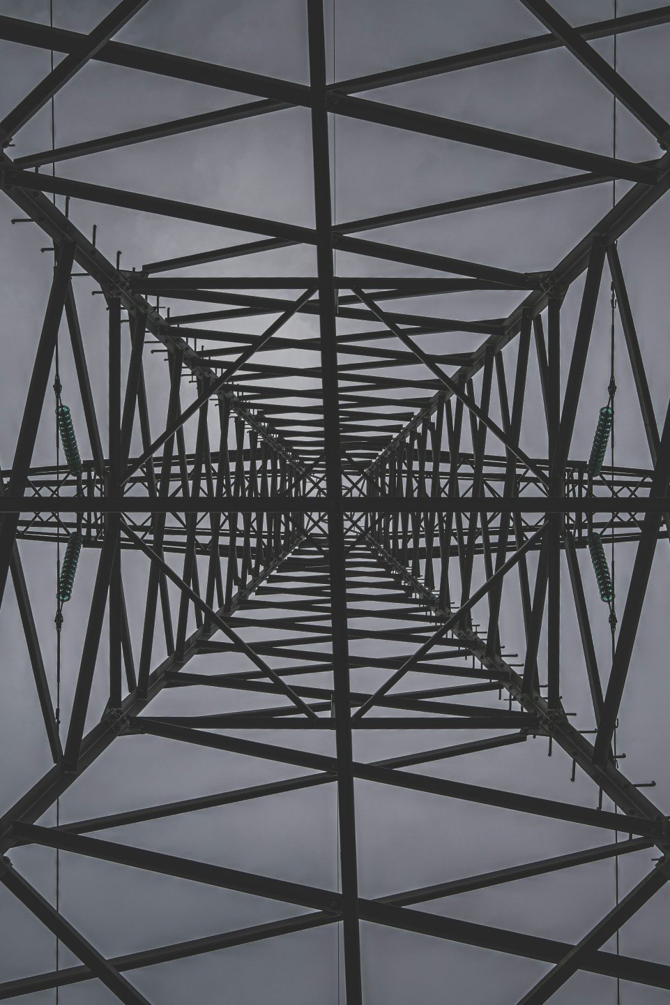 A view of an electric tower taken from the bottom, creating a symmetrical pattern