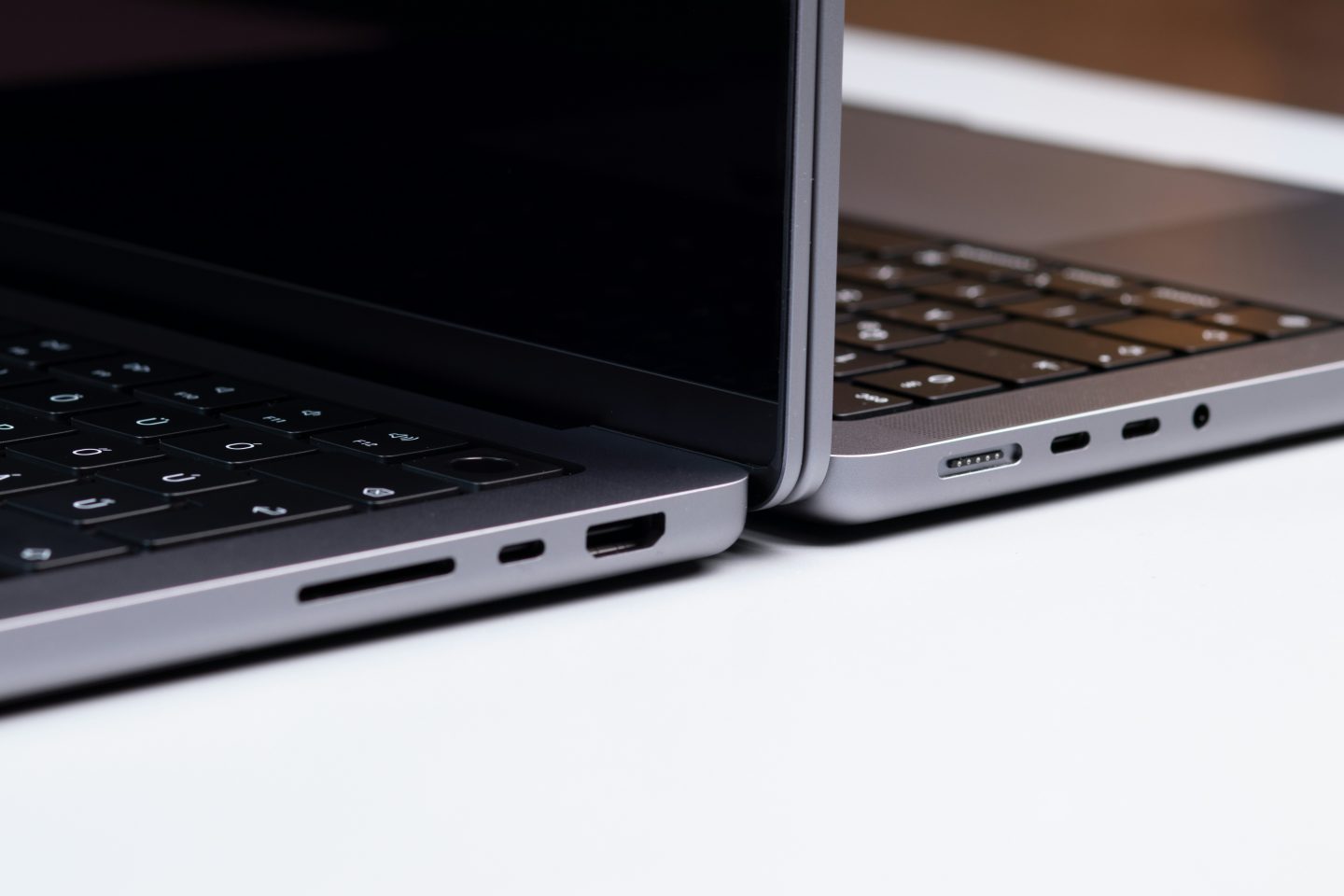 Two dark grey laptops against each other on a white table