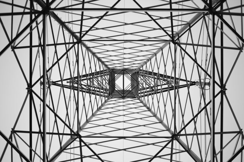A view of an electric tower taken from the bottom, creating a symmetrical pattern