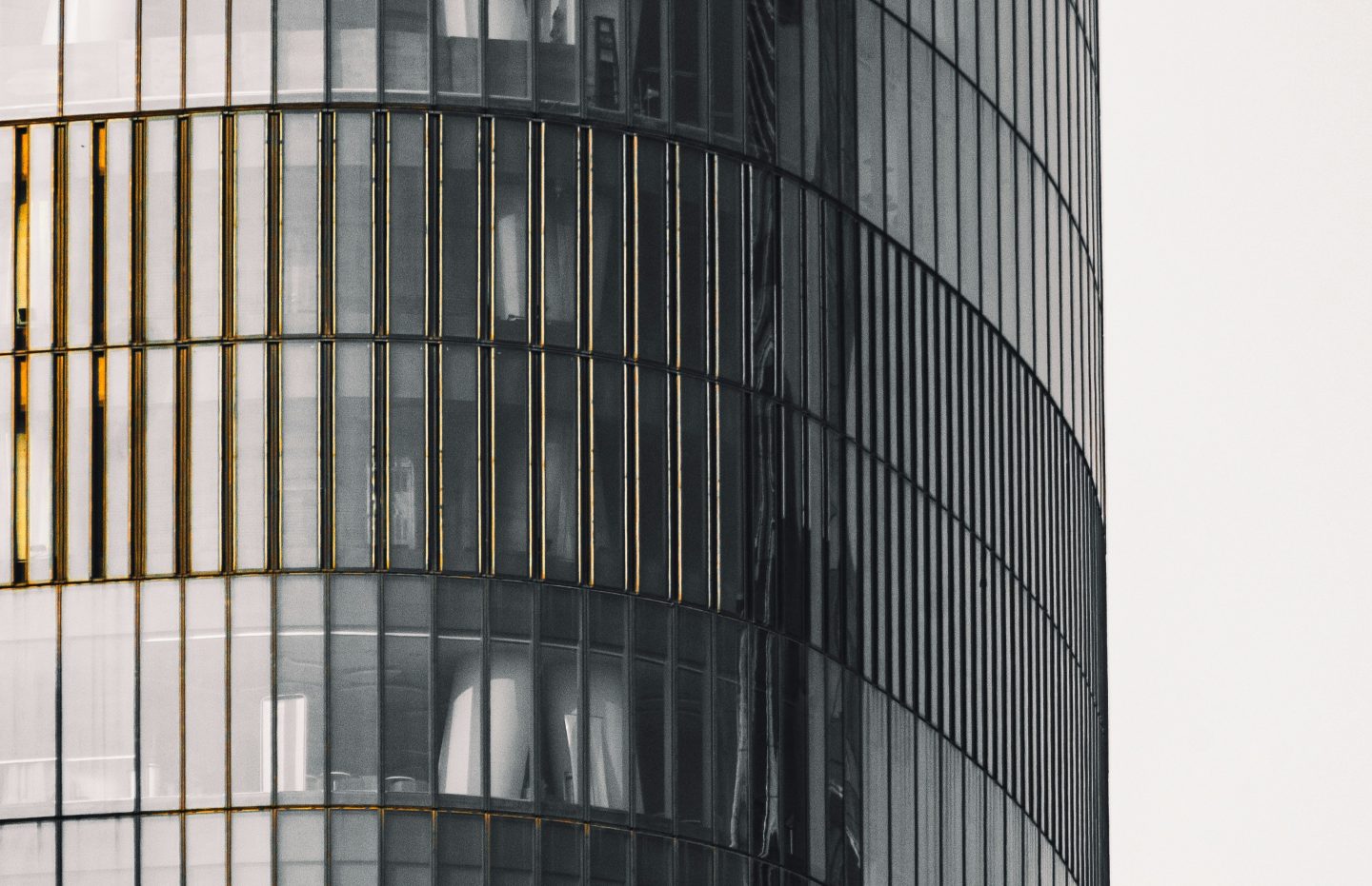 A curved grey side of a high-rise building covered in glass windows