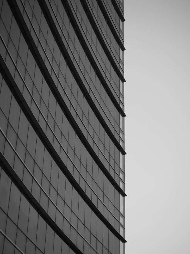 A grey side of an corporate building against a light, grey sky
