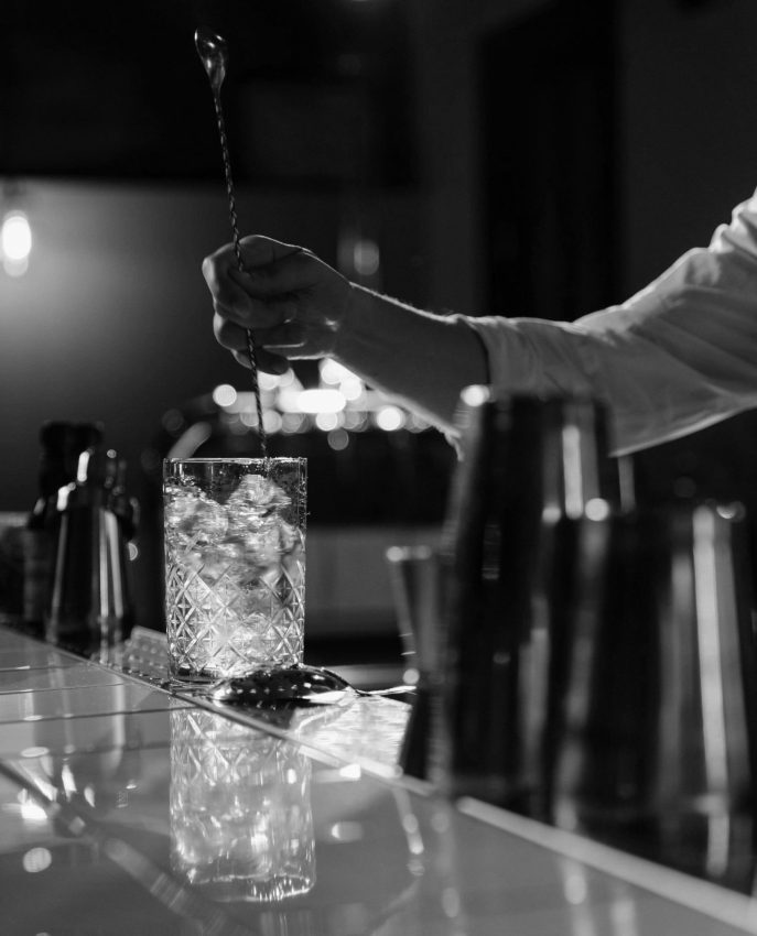 A person mixing a cocktail on a bar counter
